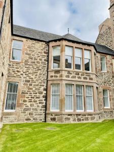 una gran casa de piedra con césped verde en No 49 a spacious executive apartment in Inverness, en Inverness