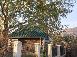 una casa in mattoni con una recinzione e un albero di Clarens Mountain Sage Cottage a Clarens