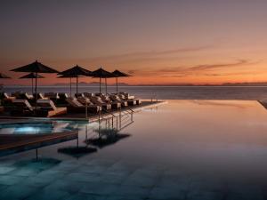 una piscina con sillas y sombrillas y el océano en Lesante Blu, a member of The Leading Hotels of the World - Adults Only, en Tragaki