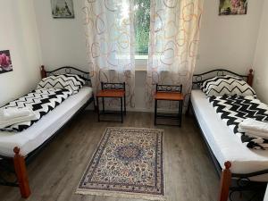 two beds in a room with a window and a rug at Ferienwohnung Julia in Vlotho