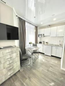 uma cozinha com armários brancos, uma mesa e uma televisão em Элегантная квартира-студия ЖК Рич Таун, Ирпень em Irpin