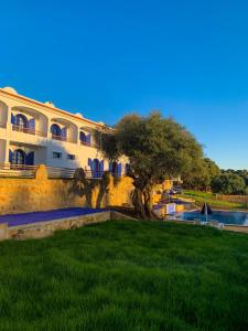 a building with a tree in front of a yard at Dmina House in Asilah