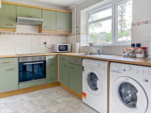 een keuken met groene kasten en een wasmachine en droger bij Elvington House, entire house, kitchen, garden, parking, wifi in Kings Lynn