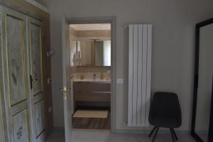 ein Bad mit einem Waschbecken und einem Stuhl neben einer Tür in der Unterkunft Cospea B&B in Terni