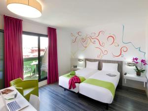 a hotel room with a bed and a desk with a laptop at Ibis Styles Madrid Prado in Madrid