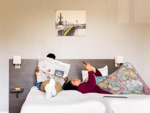 a woman laying on a bed with a laptop at Aparthotel Adagio Access Nogent sur Marne in Nogent-sur-Marne