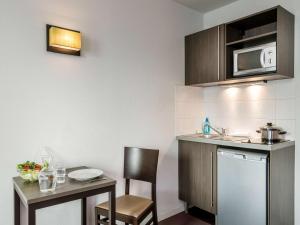 a small kitchen with a table and a microwave at Appart'hotel Vacancéole Paris Quai de Marne in Nogent-sur-Marne