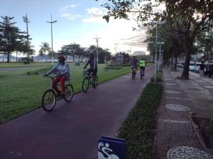 a group of people riding bikes down a sidewalk at Hotel e Pousada das Goianas in Santos