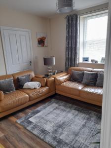 - un canapé en cuir brun dans un salon avec une fenêtre dans l'établissement College Square, Terrace House, à Bessbrook