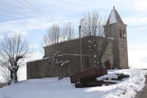 une ancienne église en briques avec une cloche dans la neige dans l'établissement Palomba Rural, à Espinilla