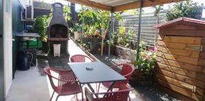 eine Terrasse mit einem Tisch, Stühlen und einem Grill in der Unterkunft Appartement spacieux in Sainte-Marie