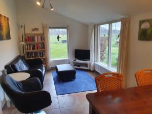 uma sala de estar com um sofá e cadeiras e uma televisão em Wagenschuur em Emst