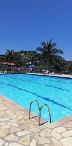 a large swimming pool with blue water and palm trees at Residencial Marina Club in São Pedro da Aldeia