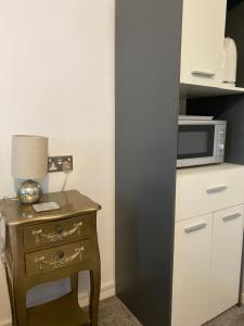 a small table with a lamp and a microwave at Tower Hill House Basingstoke in Basingstoke