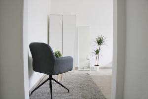 uma cadeira preta num quarto branco com plantas em New & Modern Apartment with Beautiful Lake View! em Lugano