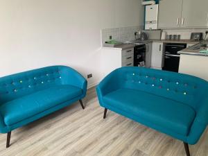 two blue couches in a room with a kitchen at The Cochno Flat, Clydebank in Dalmuir