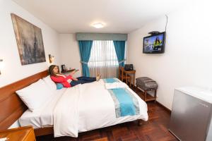 a woman sitting on a bed in a hotel room at Samana Hotel in Arequipa