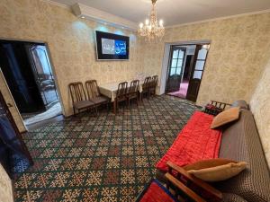 uma sala de estar com um sofá, uma mesa e cadeiras em Guest House Eles em Karakol