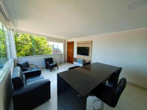 uma sala de estar com uma mesa preta e cadeiras em Apartamento Novo em Iriri - Vista para o Mar em Iriri