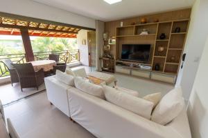 a living room with a white couch and a television at Residencial Ykutiba- Imbassaì Ap A-103 in Imbassai