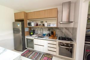 a kitchen with a stainless steel refrigerator and white cabinets at Residencial Ykutiba- Imbassaì Ap A-103 in Imbassai