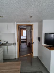 eine Küche mit einer Tür, die sich zu einer Küche mit einem TV öffnet in der Unterkunft FeWo Iris in Alsfeld