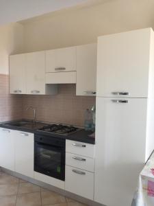 a white kitchen with a stove and a refrigerator at Ginepro family in Valledoria