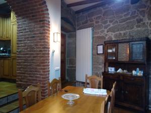ein Esszimmer mit einem Tisch und einer Ziegelwand in der Unterkunft Vivienda Turísitica A Petada de San Clodio in Gomariz