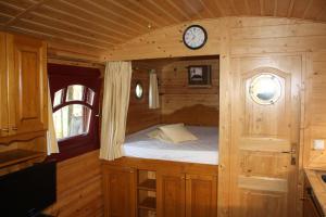 a small bed in a wooden room with a clock at La Gypsy Caravane in Rivière
