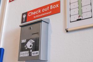 a check out box on a wall with a sign at Hammerbrook Hostel in Hamburg