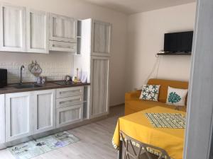 a kitchen with white cabinets and a yellow table at Appartamenti Renzo&Rita1 Jolanda in SantʼAntìoco