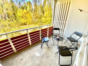 four chairs sitting on a balcony with a view of trees at DP Apartments Vaasa IV in Vaasa