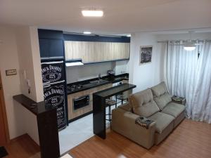 a living room with a couch and a kitchen at Apartamento CONFORT CLUB FRENTE MAR completo. in Barra Velha