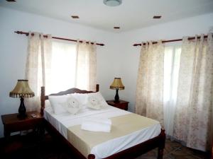 a bedroom with a bed with white sheets and windows at Chalets Anse Possession in Baie Sainte Anne