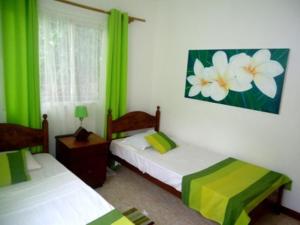 two beds in a room with green curtains at Chalets Anse Possession in Baie Sainte Anne