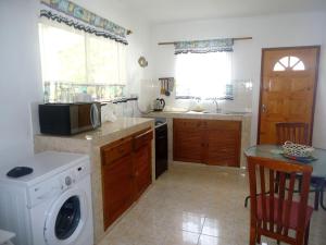 a kitchen with a washing machine and a microwave at Chalets Anse Possession in Baie Sainte Anne