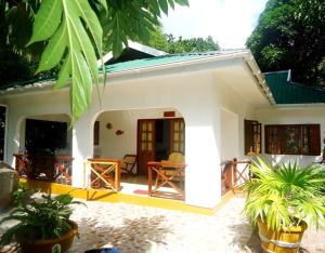 a white house with plants in front of it at Chalets Anse Possession in Baie Sainte Anne