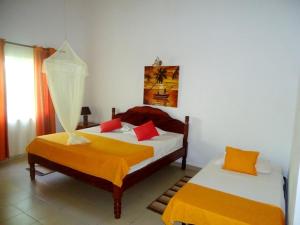 a bedroom with two beds with orange and white sheets at Chalets Anse Possession in Baie Sainte Anne
