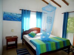 a bedroom with a bed with blue drapes at Chalets Anse Possession in Baie Sainte Anne