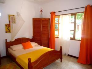 a bedroom with a bed with an orange pillow and a window at Chalets Anse Possession in Baie Sainte Anne