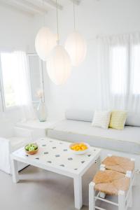 ein weißes Wohnzimmer mit einem Tisch und Obst darauf in der Unterkunft Agnandi Cielo in Tourlos