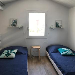 2 Betten in einem kleinen Zimmer mit Fenster in der Unterkunft Maison à 300m de la plage, quartier calme in Mimizan