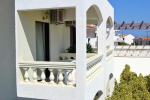 a white building with a balcony with a window at To Spiti Tis Eirinis in Poros