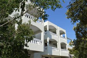 ポロスにあるTo Spiti Tis Eirinisの白いバルコニーと木々が備わるアパートメントビル