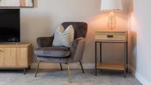 una silla con una almohada junto a una mesa auxiliar en Leeward House - Donnini Apartments, en Ayr