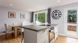 cocina y comedor con mesa y reloj en la pared en Leeward House - Donnini Apartments, en Ayr