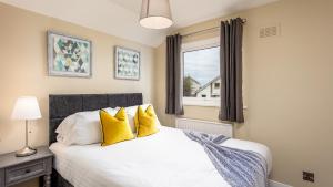 Un dormitorio con una cama con almohadas amarillas y una ventana. en Leeward House - Donnini Apartments, en Ayr