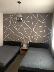 ein Schlafzimmer mit 2 Betten und einer geometrischen Wand in der Unterkunft aspa2 in Platamonas