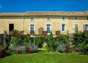 un antiguo edificio de piedra con flores en un patio en Abacard Home Gite adult only, en Roquemaure