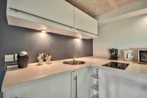 een kleine keuken met witte kasten en een spoelbak bij Valletta Timeless Elegance : City Centre Apartment in Valletta